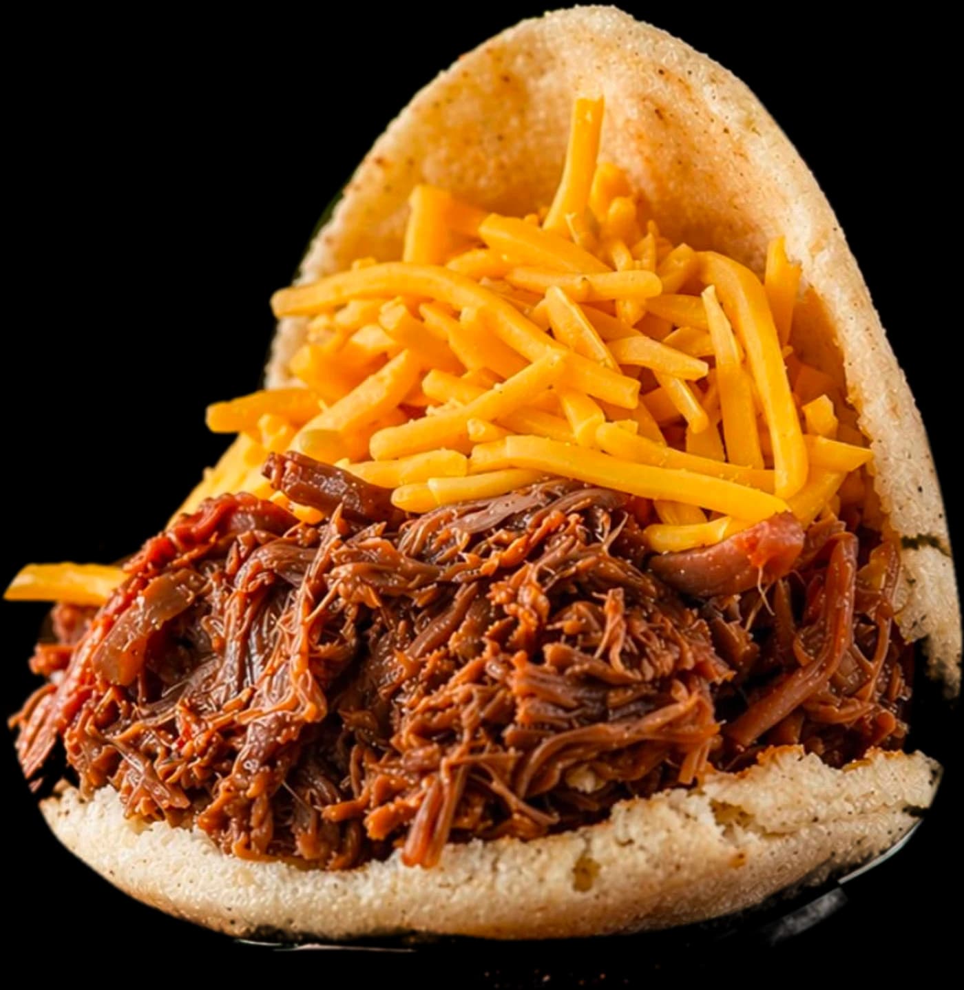 Shredded beef arepa topped with cheddar, in a Sazón wrap
